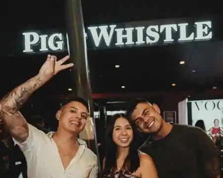 Group of friends posing under the Pig 'N' Whistle signage at night in Fortitude Valley, Brisbane — salsa, bachata venue in Brisbane