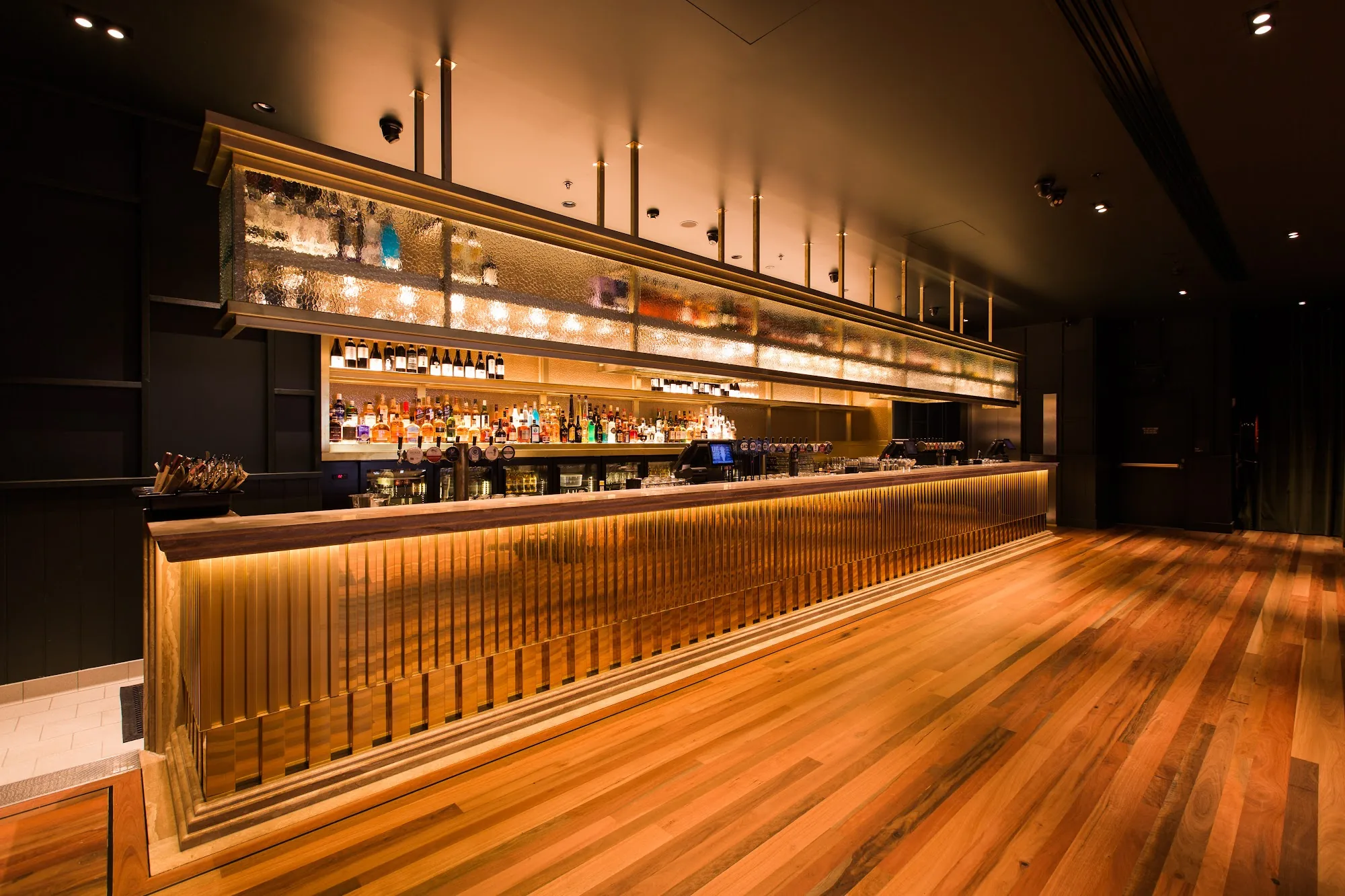 Long polished bar with warm lighting and wooden dance-floor at Pig 'N' Whistle Fortitude Valley, Brisbane