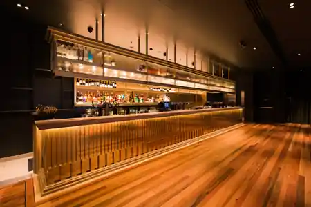 Long polished bar with warm lighting and wooden dance-floor at Pig 'N' Whistle Fortitude Valley, Brisbane — salsa, bachata venue in Brisbane