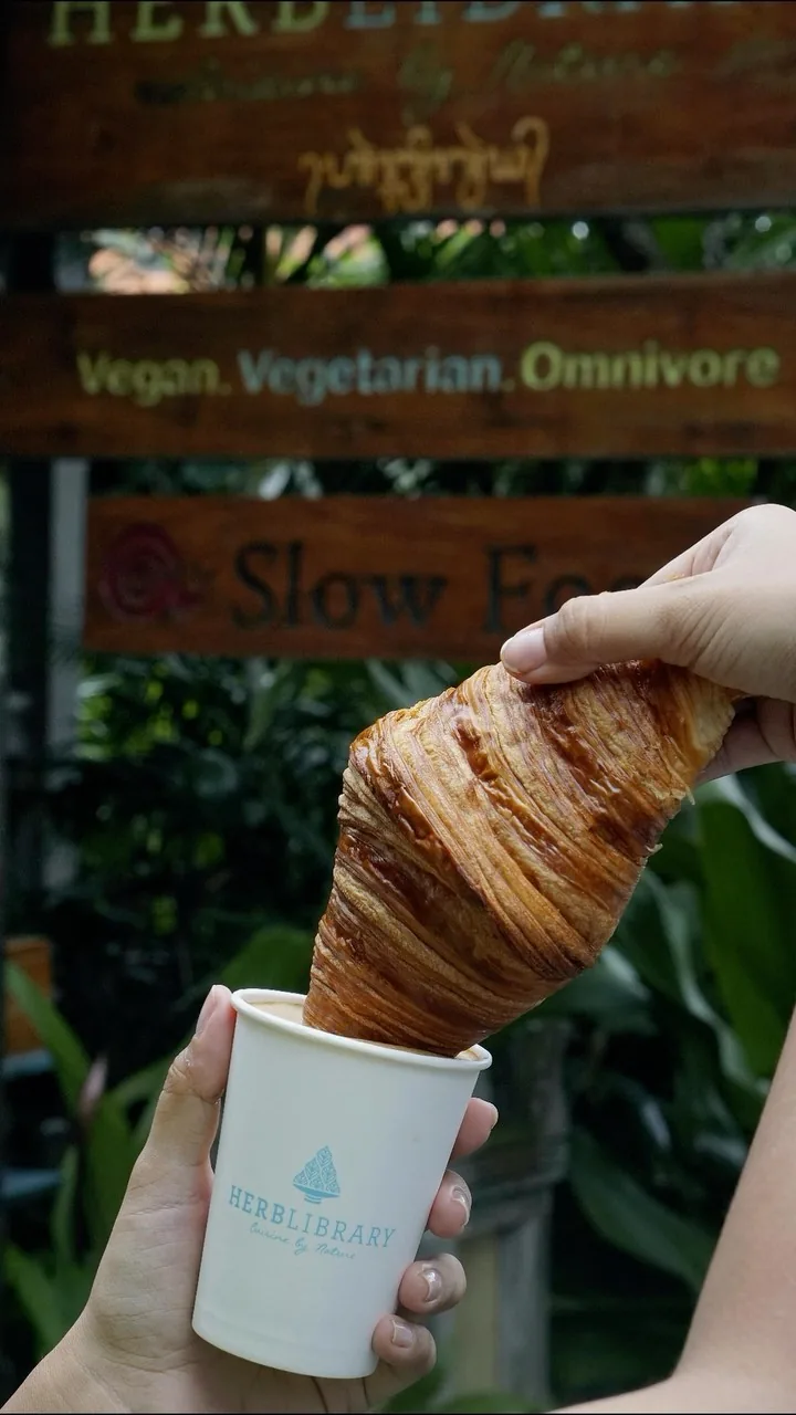 Herb Library Ubud entrance signage with croissant and branded coffee cup — bachata, salsa, kizomba venue in Bali
