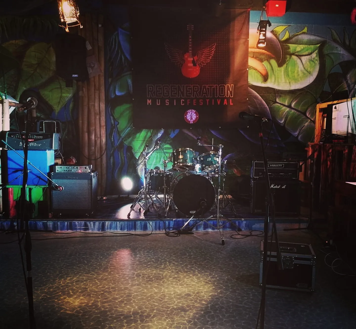 Stage setup with drum kit and colorful murals at Dandarì Disco Pub Villanova Italy