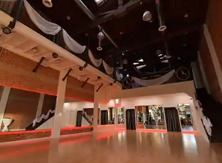Dance Street California studio interior in Pasadena featuring a spacious hardwood dance floor with mirrored walls, ambient red lighting, exposed brick, and elegant draping, kizomba venue in Pasadena