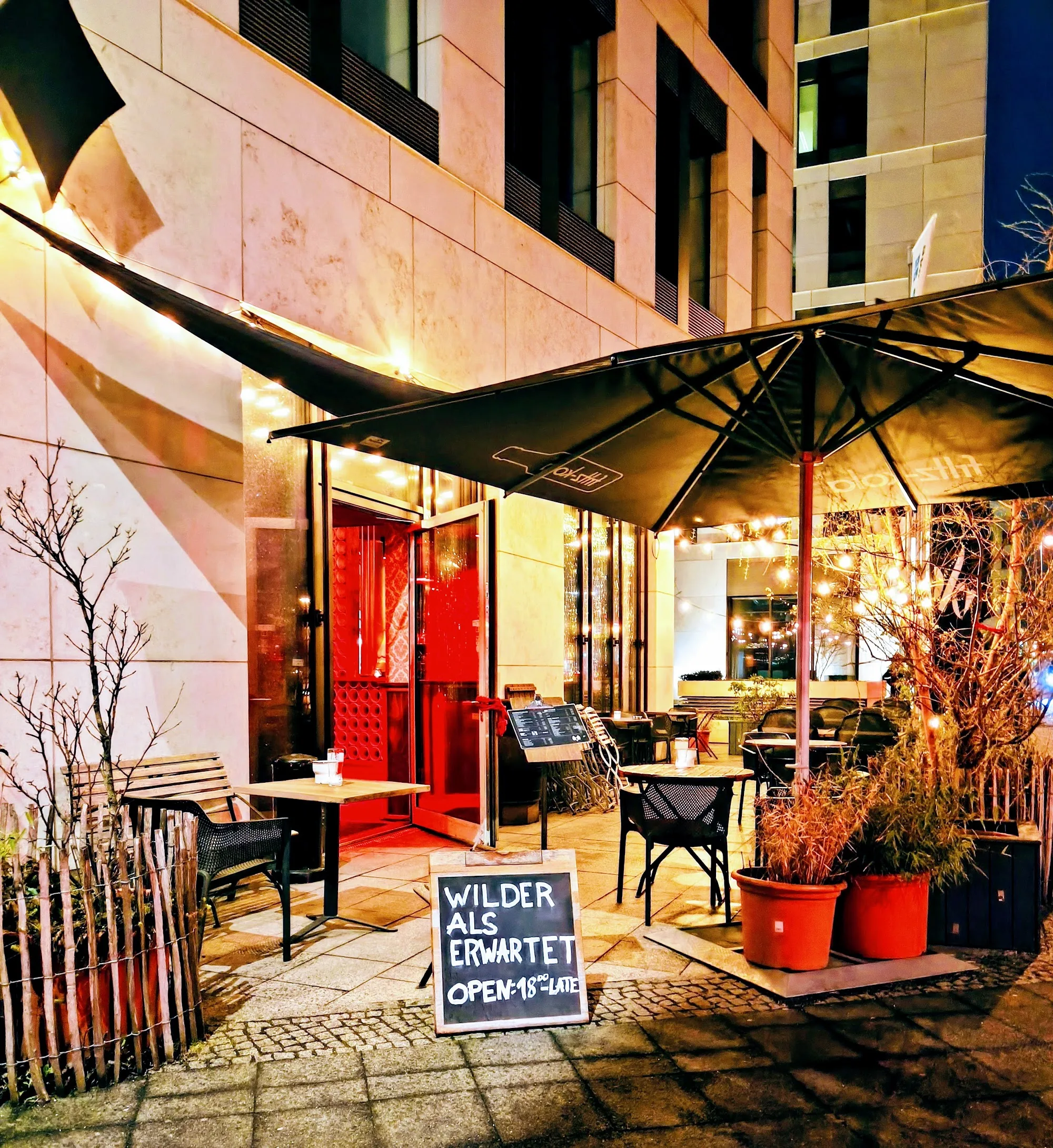 Wilder als erwartet Bar entrance at night with branded signage in Berlin