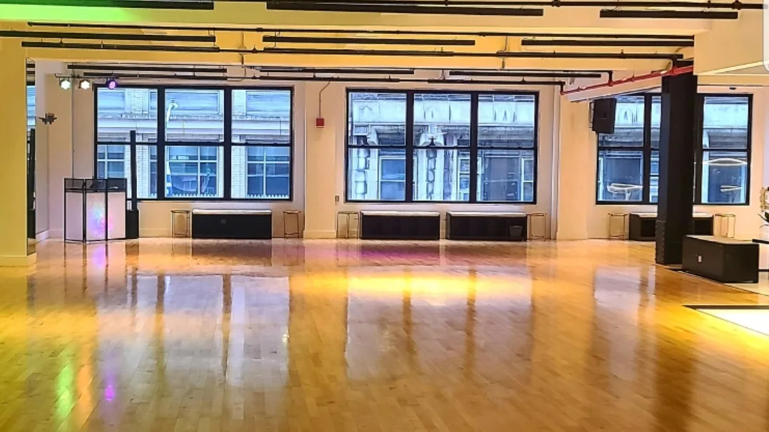 Sunlit wooden dance floor and tall windows inside EPA Dance Academy studio in New York