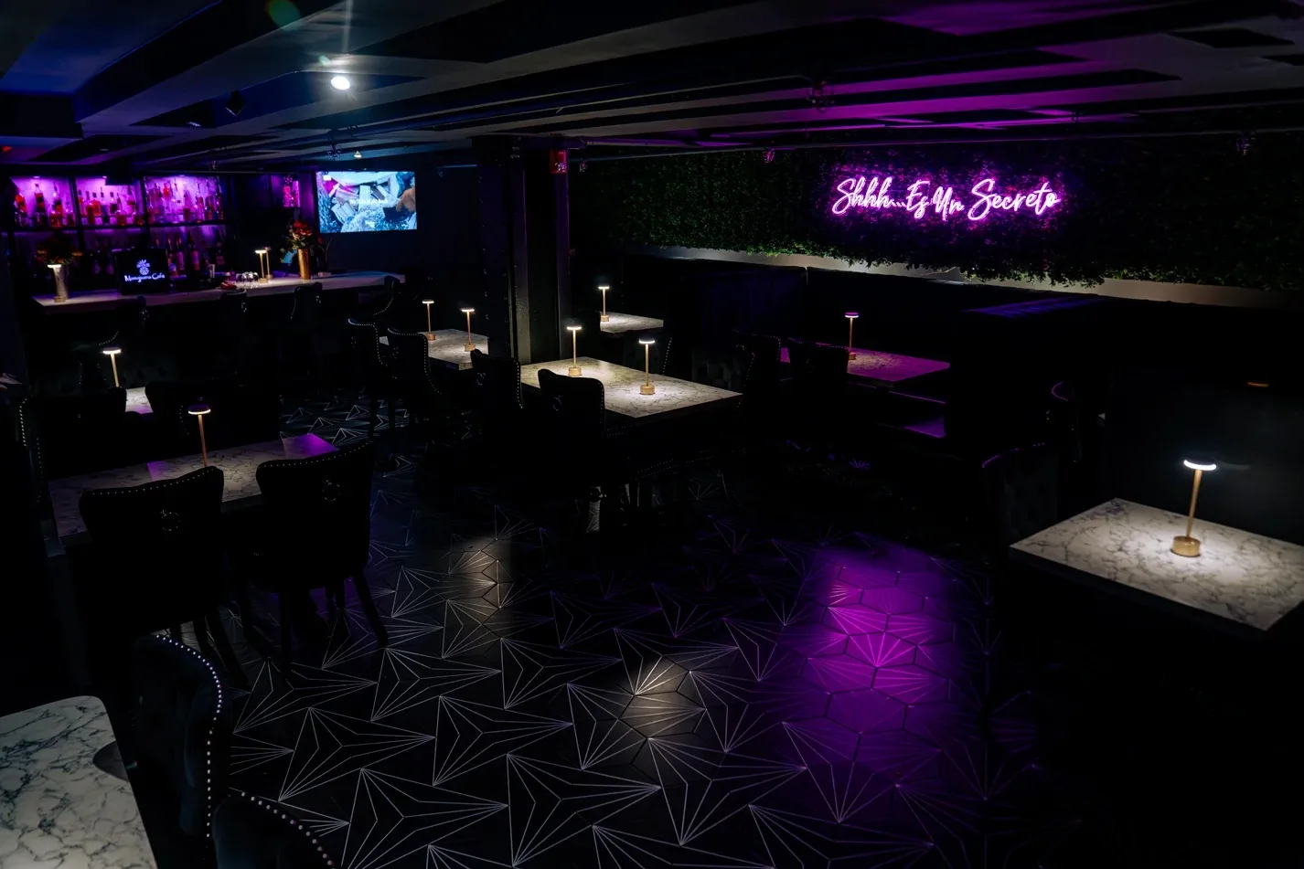 Purple-lit lounge with marble tables and neon sign at Mamajuana Cafe, Houston