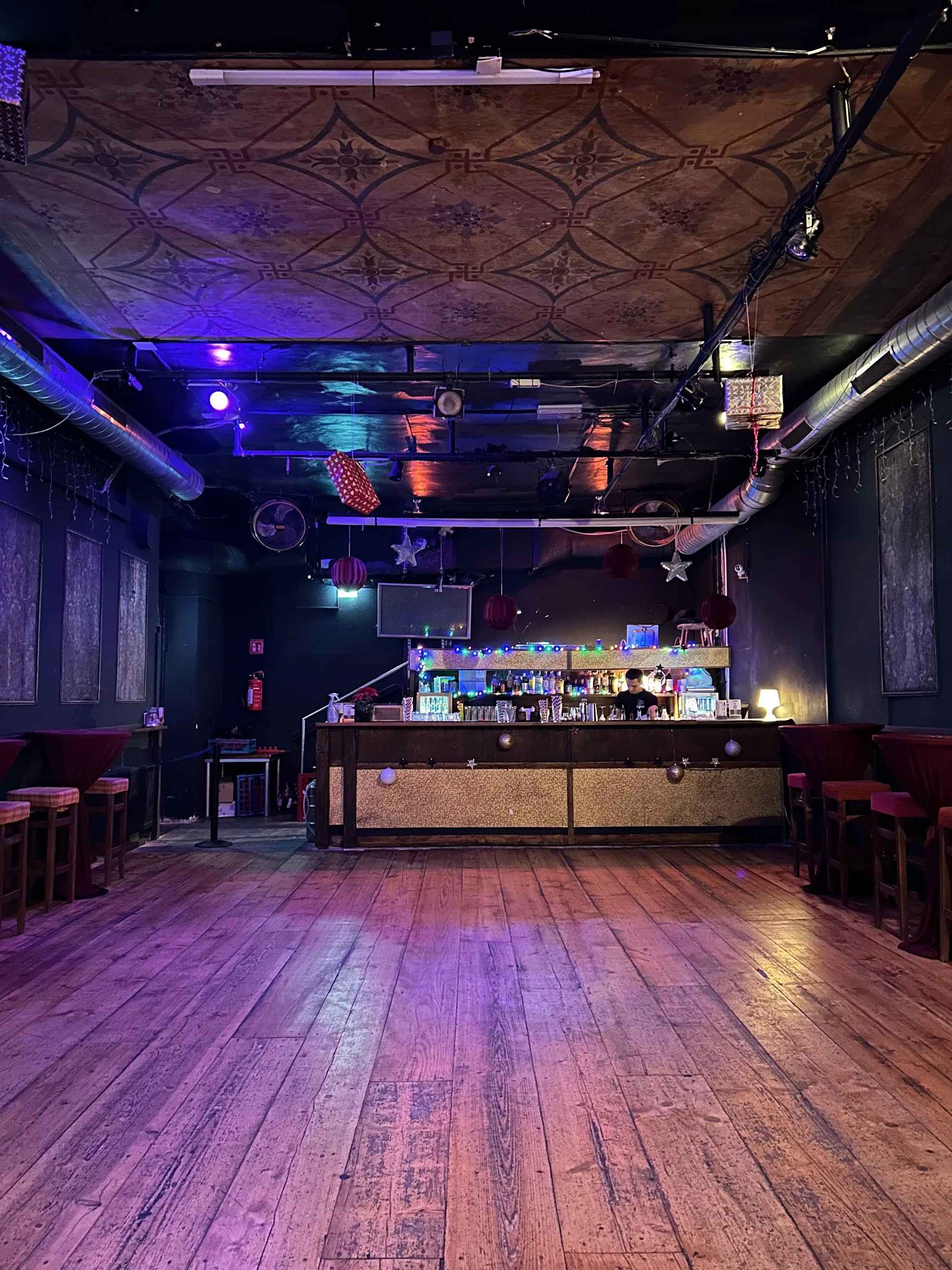 Empty wooden dance floor and bar at Casa Mestiza Vienna with purple lighting