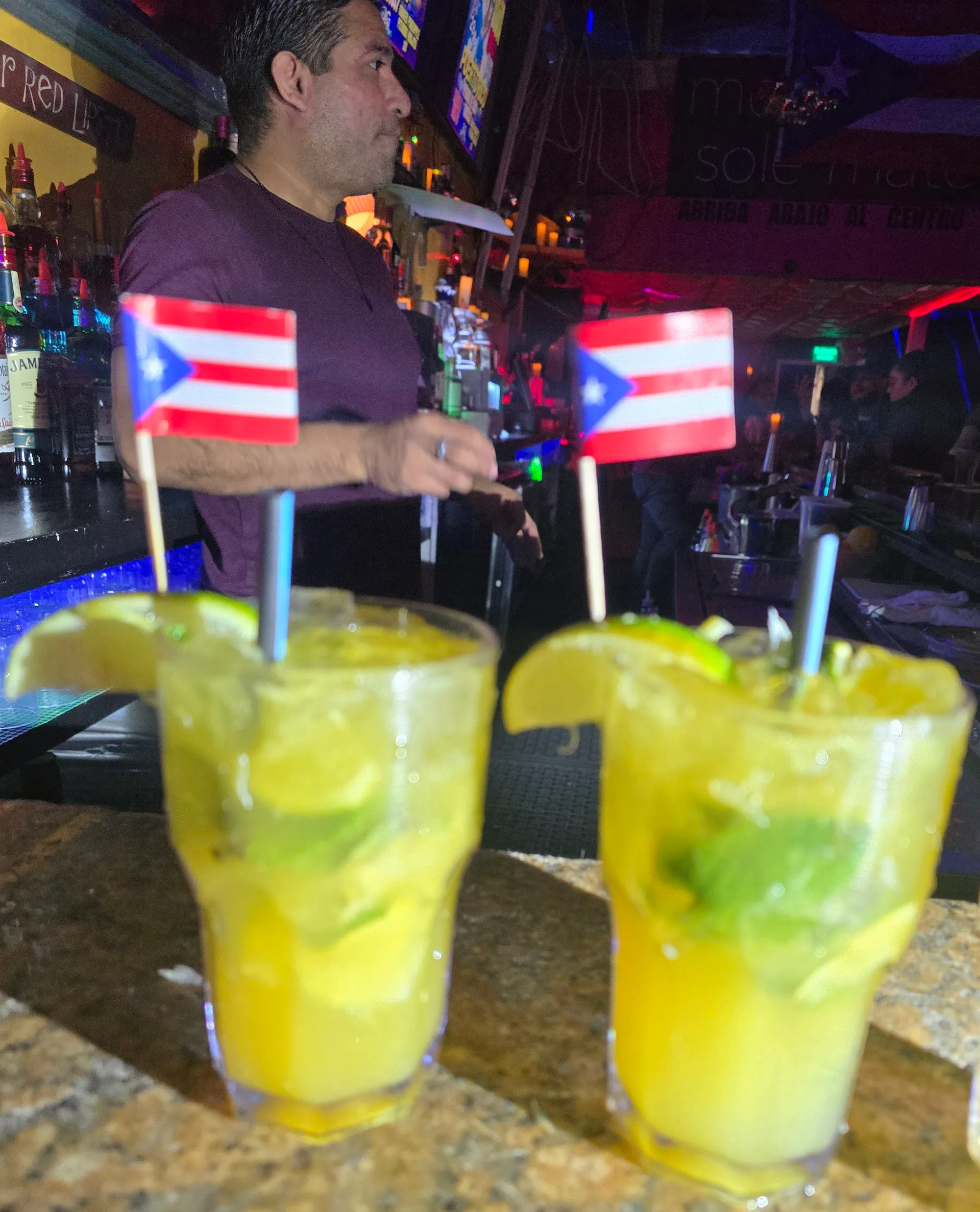 Bartender serving cocktails at the bar with Puerto Rican flag picks at Cafe Citron, Washington, D.C.