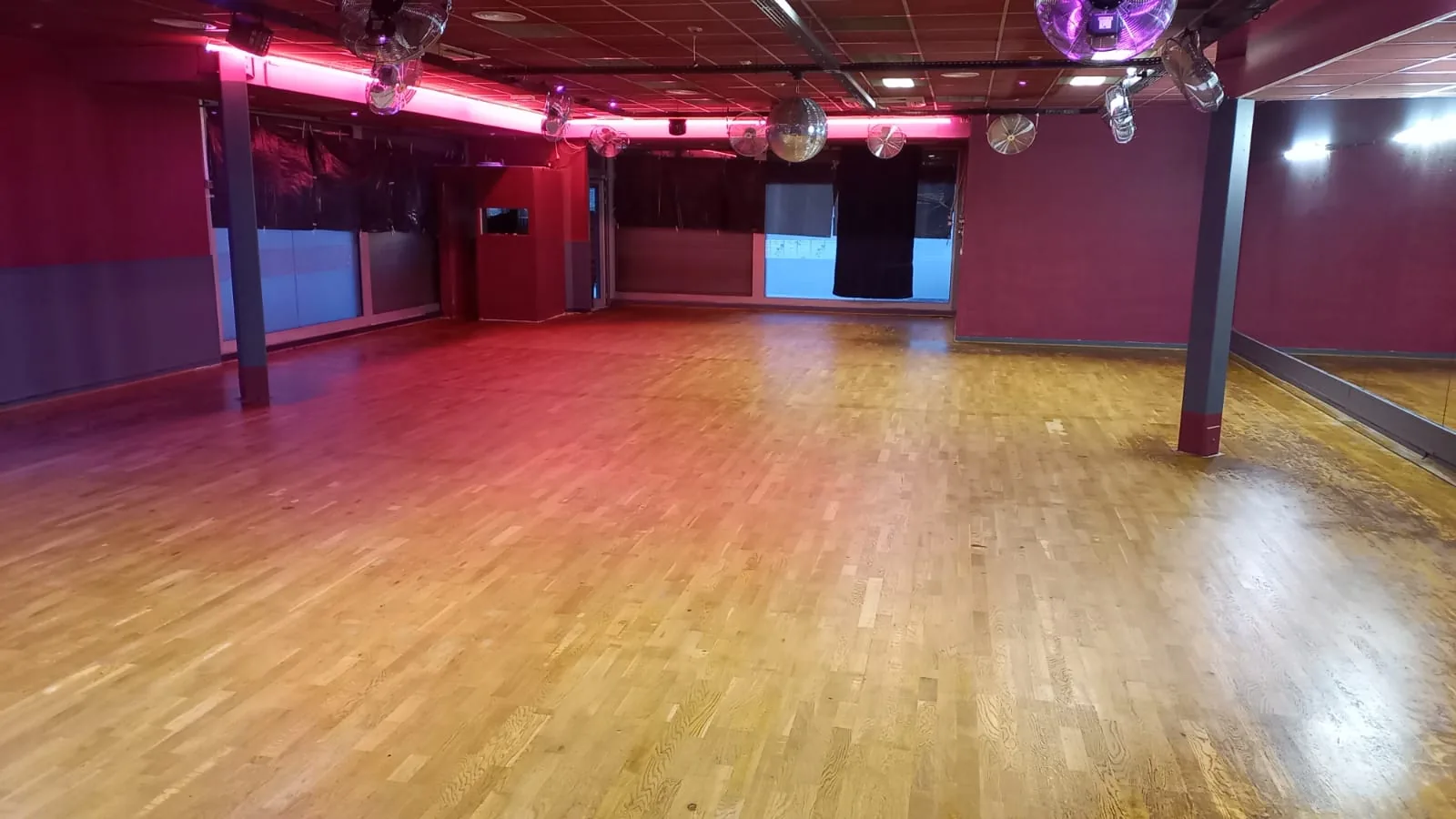 Empty wooden dance floor with mirrored wall and disco balls at Sensation Dance School studio in Paris