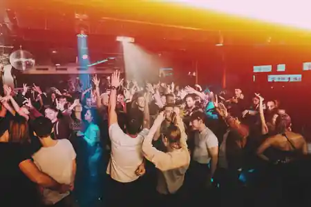 Packed dance floor with disco ball and crowd dancing under stage lights at O'Sullivans by the Mill, Paris — salsa venue in Paris