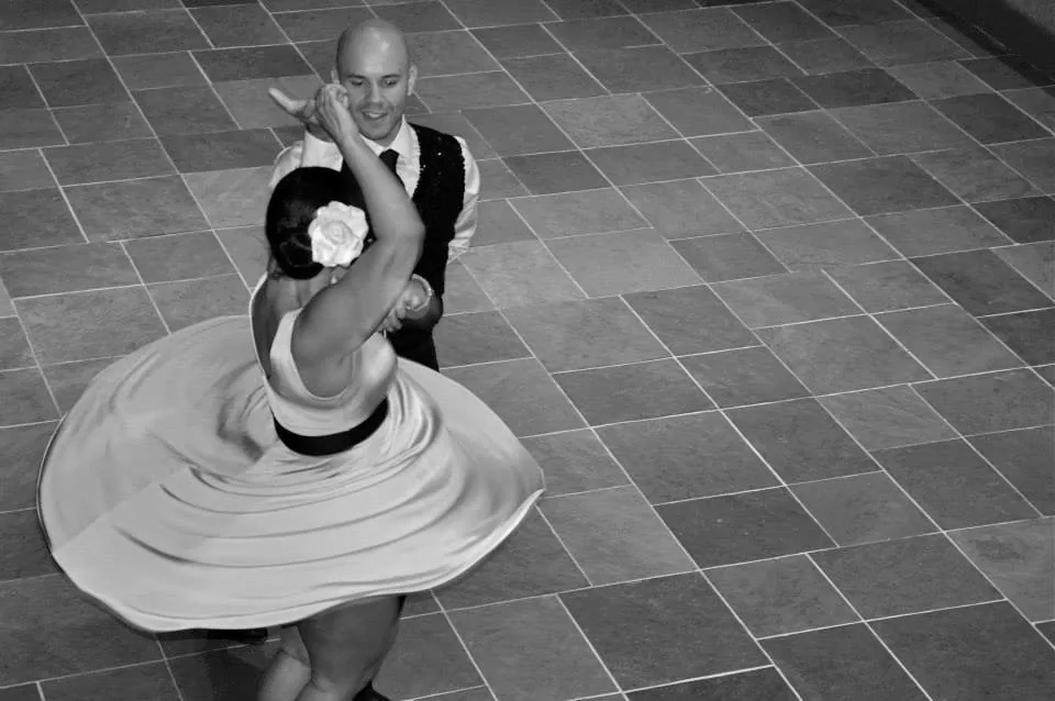 Couple performing a social dance at Pasofino Dance in Atlanta with the woman's flowing skirt captured mid-spin on the dance floor — salsa venue in Atlanta