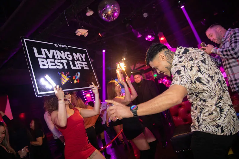 Crowd social dancing under club lighting and a disco ball at Sevilla Nightclub, San Diego