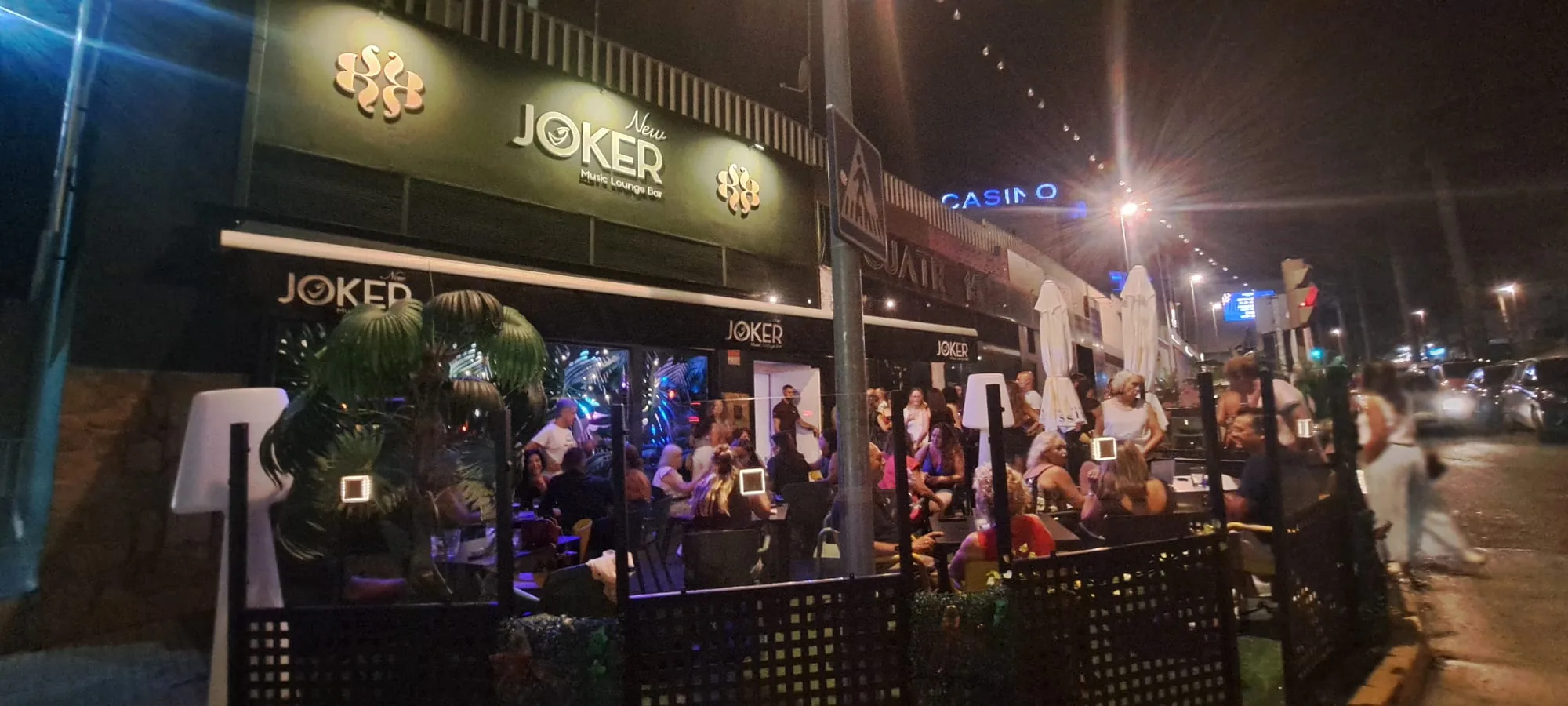 New Joker Music Lounge Bar in Tomares Spain — branded nighttime exterior with crowd inside and Joker sign