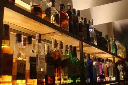 New Joker Music Lounge Bar Tomares — backlit bar shelf with colourful spirits bottles — salsa, bachata, kizomba venue in Tomares