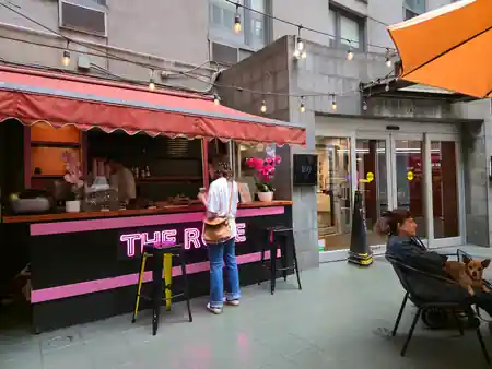 The Rose NYC patio entrance with customers and pink neon signage in New York — salsa, bachata, kizomba, zouk venue in New York