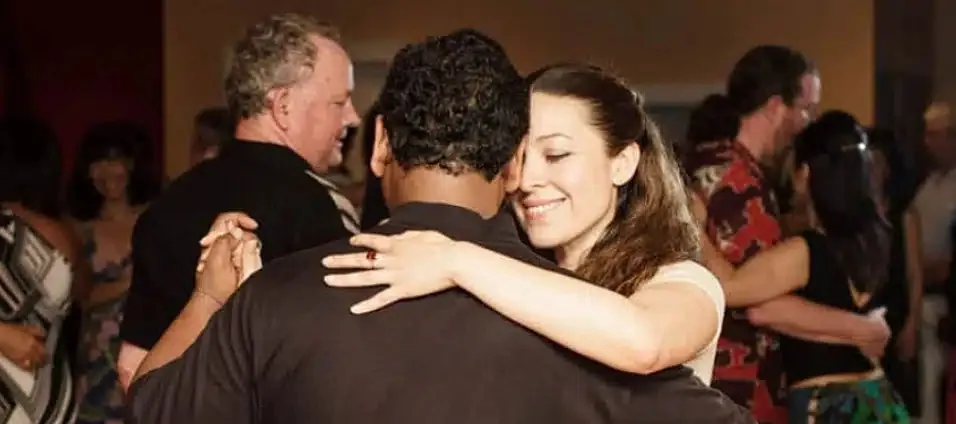 Adult couples partner dancing together at a social in a warmly lit room at LaVida Dance Studio, Seattle.