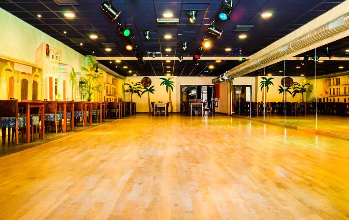 Cuban-themed dance hall with wooden floor and stage lights at Azúcar Dansatelier, Brugge