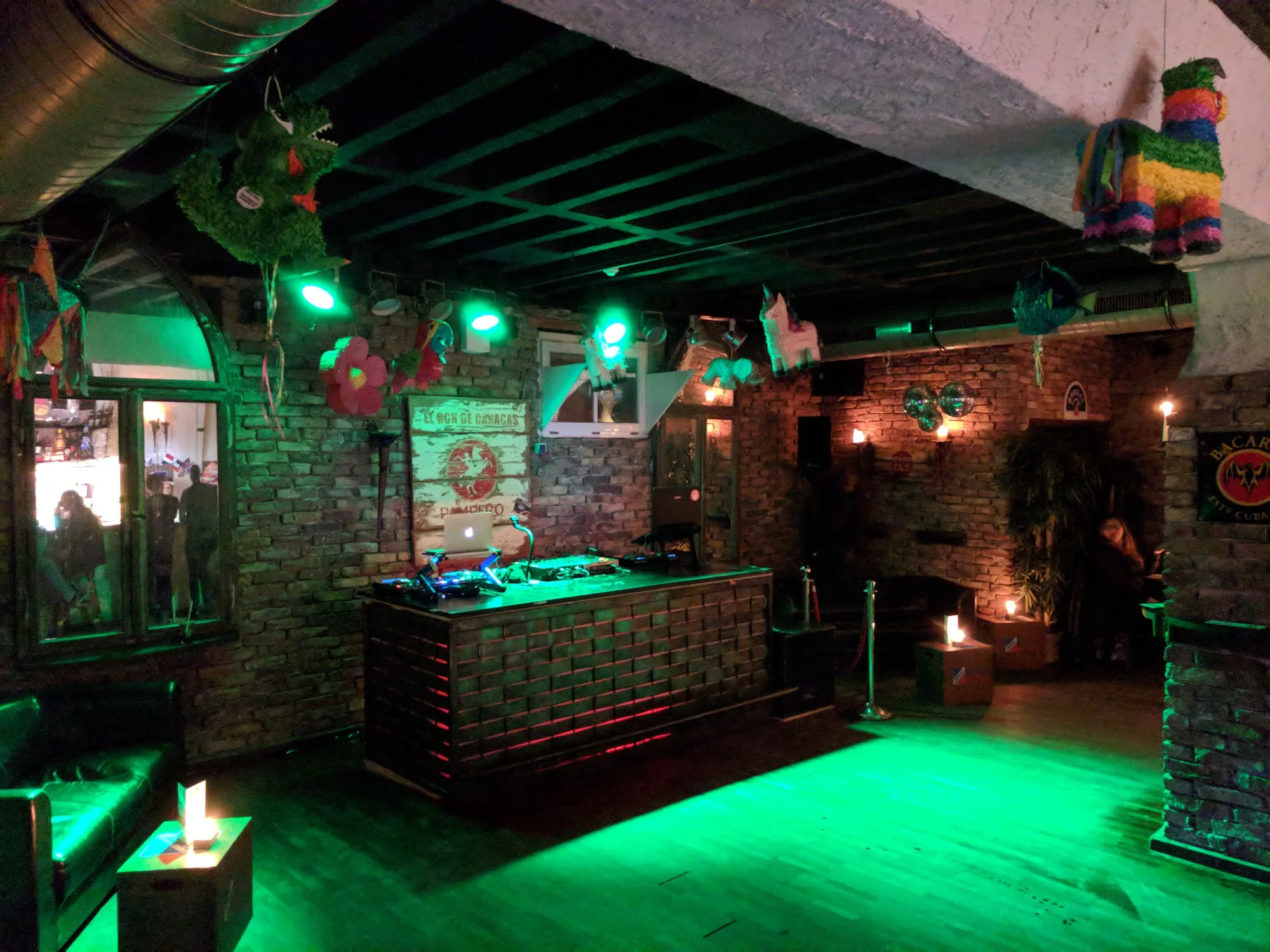 DJ booth with green dance floor and pinata decorations at Club Fogon Nuremberg