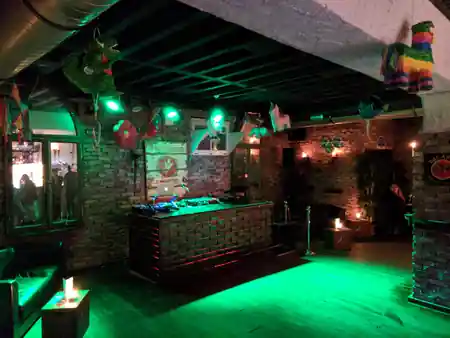 DJ booth with green dance floor and pinata decorations at Club Fogon Nuremberg — salsa, bachata venue in Nuremberg