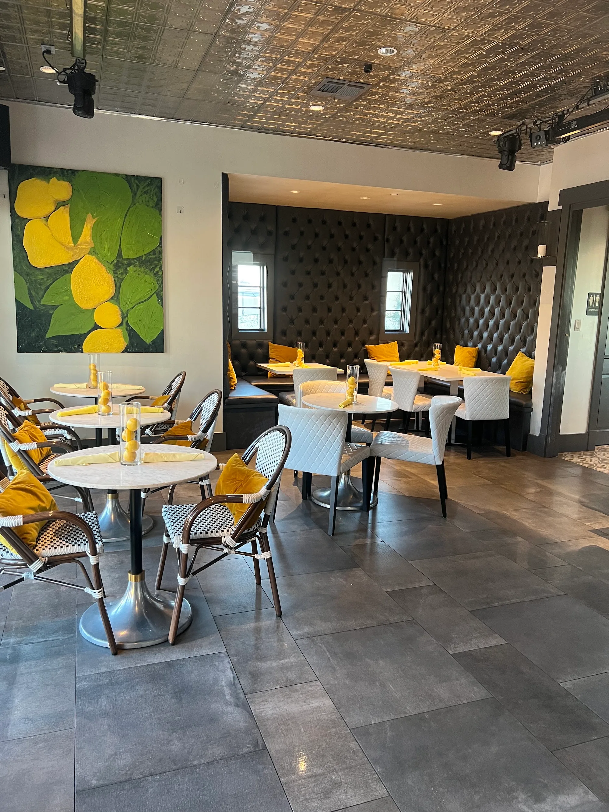 Bistro dining room with lemon artwork and tufted banquette at Ivy Bar & Bistro, Houston