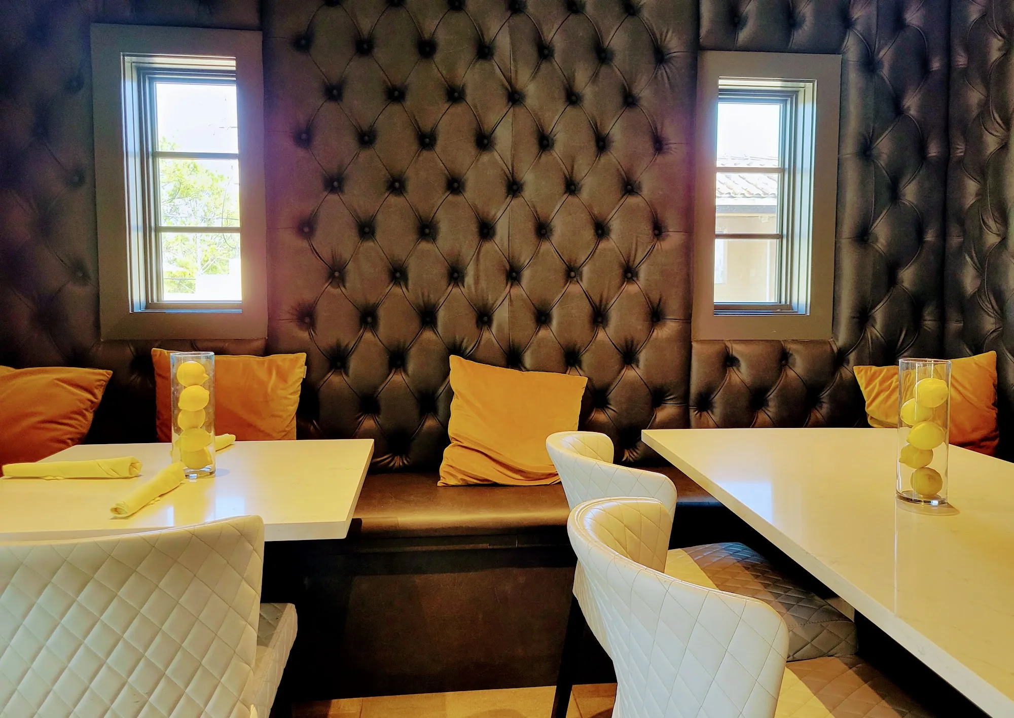 Tufted banquette seating with yellow accents at Ivy Bar & Bistro, Houston