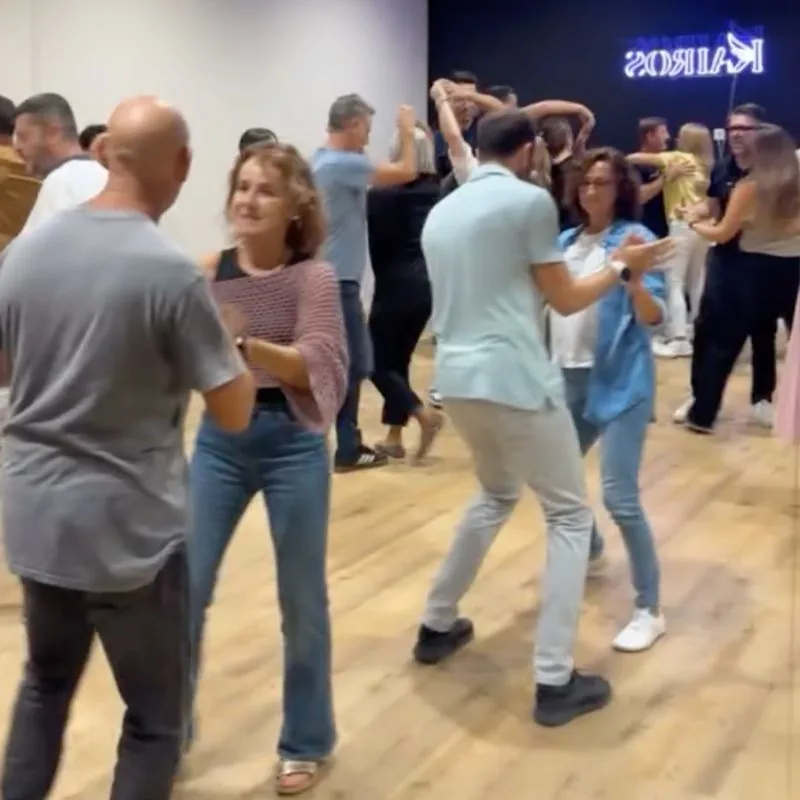 Salsa social dancers on the wooden floor under the Kairos neon sign in Mallorca