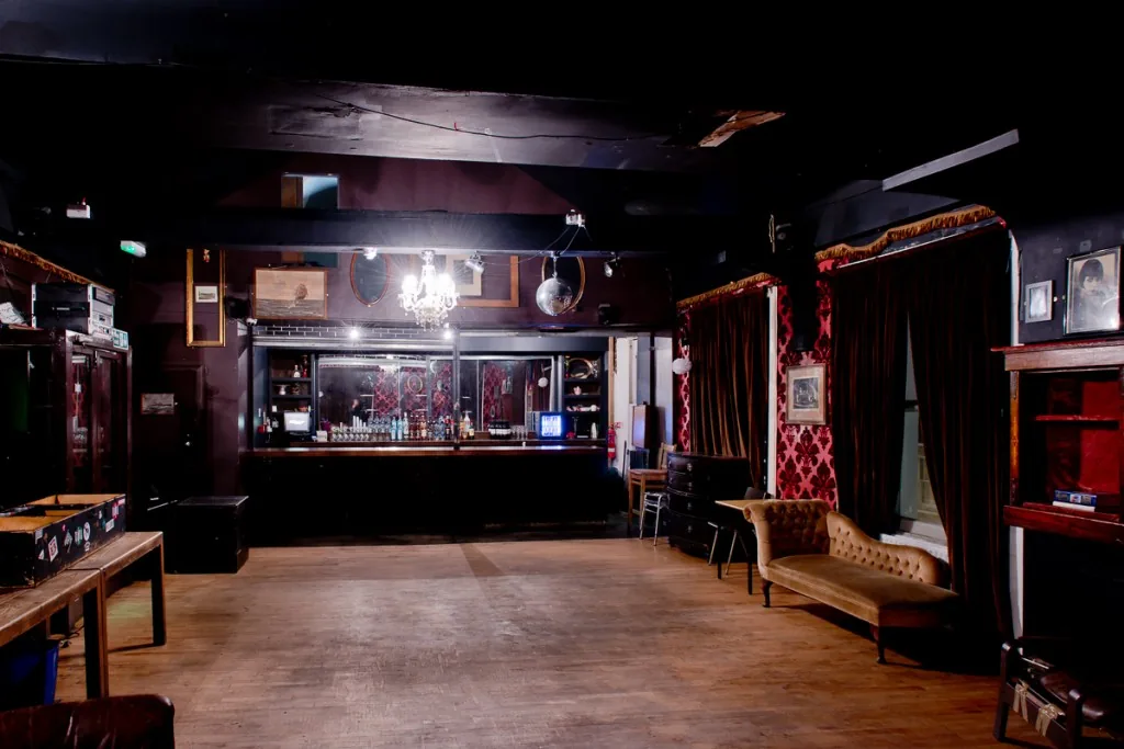 Dogstar Brixton upstairs dance floor and bar with disco ball, chandelier, and velvet curtains