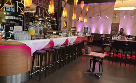 Full bar and dining area with pendant lamps and bar stools at Barfusz Leipzig — salsa, bachata venue in Leipzig