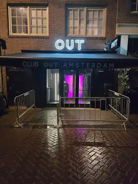 OUT Latin Club Amsterdam exterior at night — Club Out Amsterdam neon sign glowing purple above entrance — bachata, salsa venue in Amsterdam