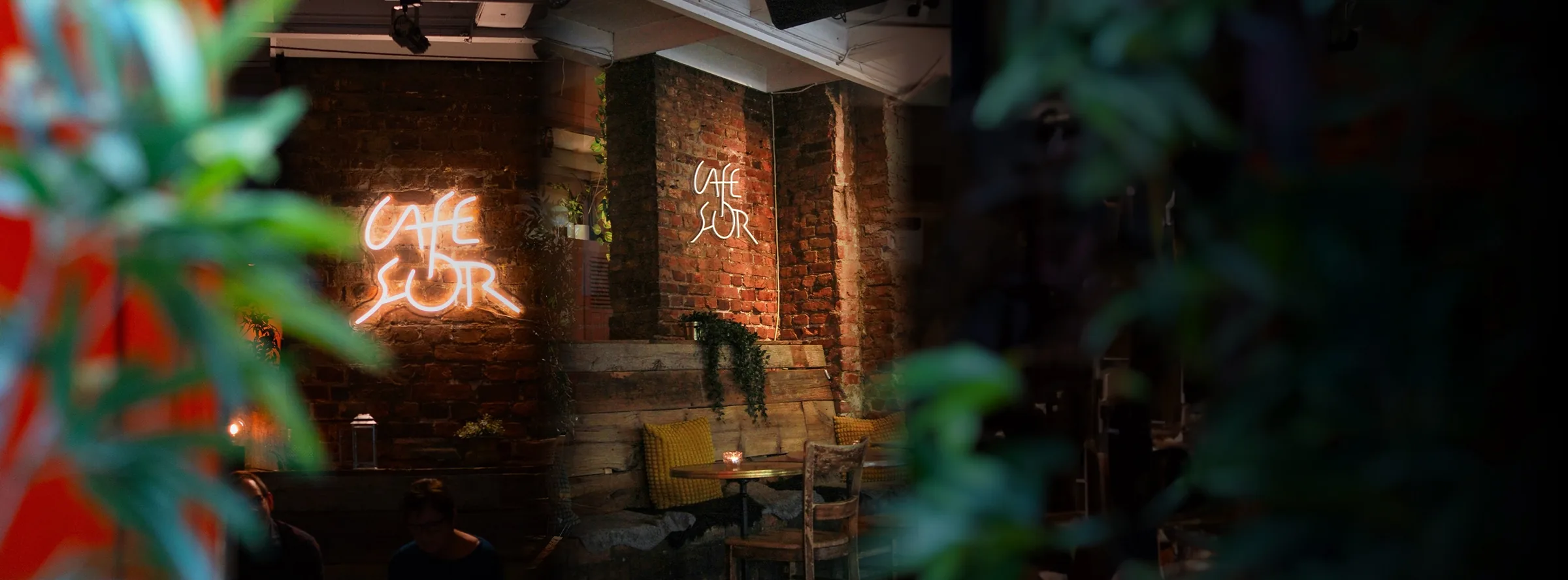 Glowing Cafe Sor neon signs on an exposed brick interior wall in Oslo