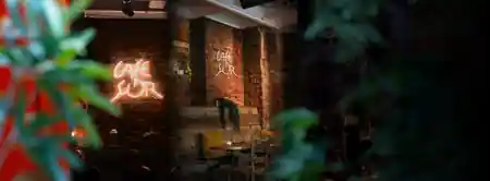 Glowing Cafe Sor neon signs on an exposed brick interior wall in Oslo, salsa, bachata venue in Oslo