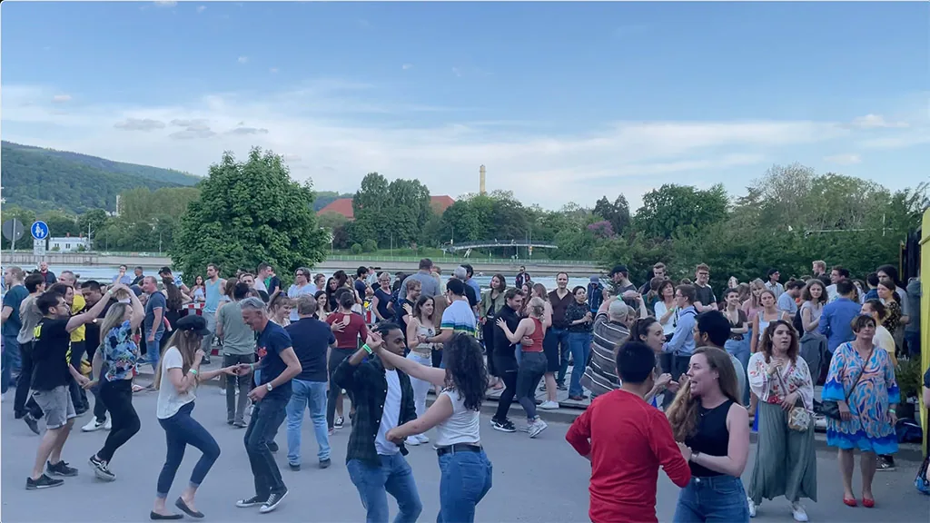 Outdoor salsa social with crowd dancing by the river in Heidelberg, hosted by El Templo