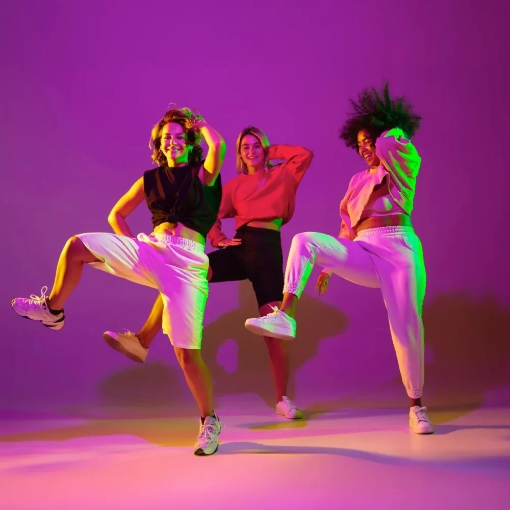 Three dancers in vibrant neon studio lighting at Uppsala Danscenter in Uppsala
