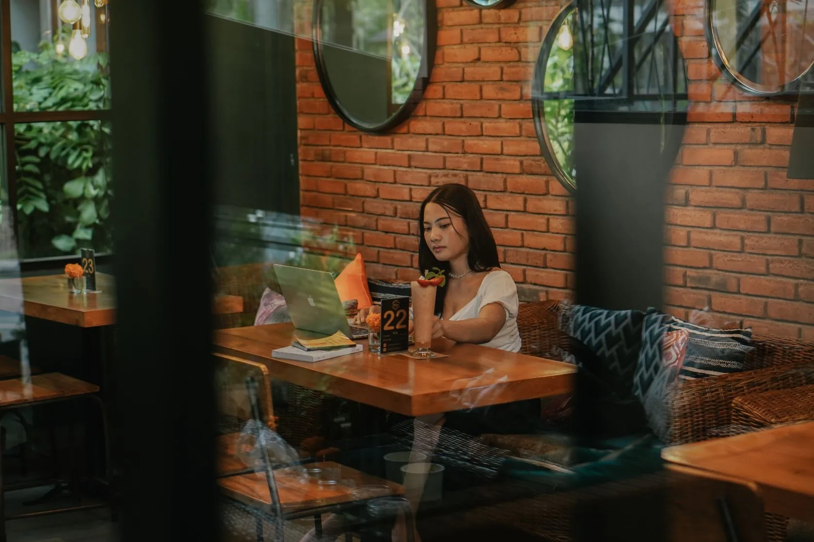 Interior view of Pilleyar Bar & Kitchen Bali with brick walls, round mirrors and lush greenery