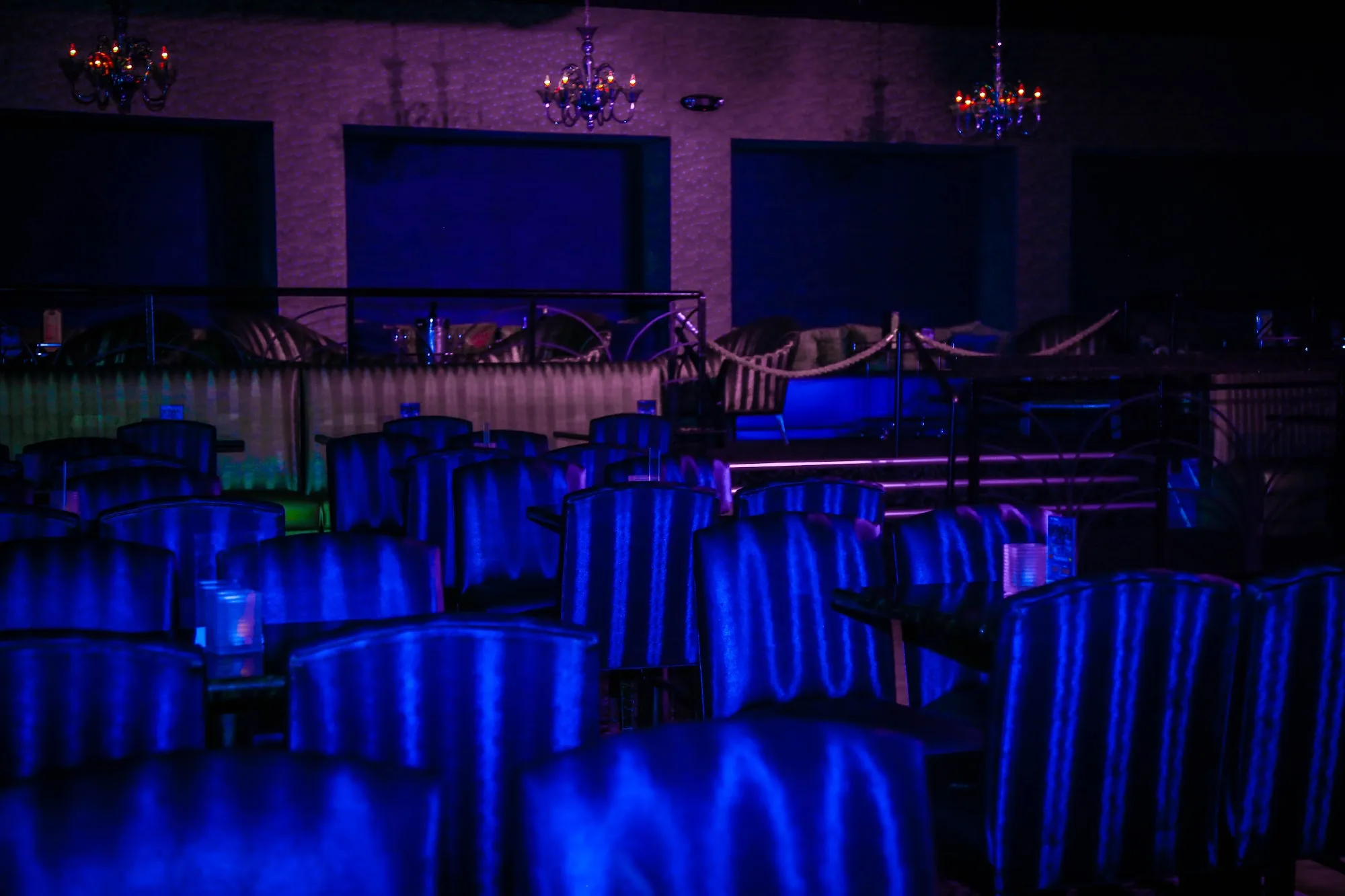 Blue-lit upholstered seating and mezzanine level at Club Tropicana, Houston