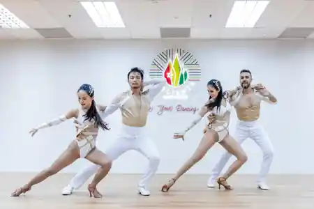 Latin dance troupe posing in front of Caliente Dance Studio neon sign Singapore — salsa, bachata venue in Singapore