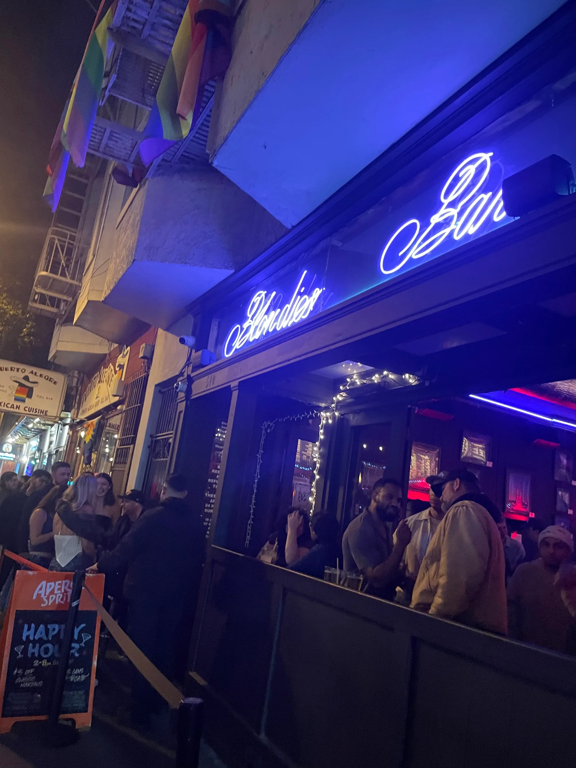 Blondie's Bar nighttime exterior with glowing blue neon signage and crowd at the entrance on Valencia Street San Francisco