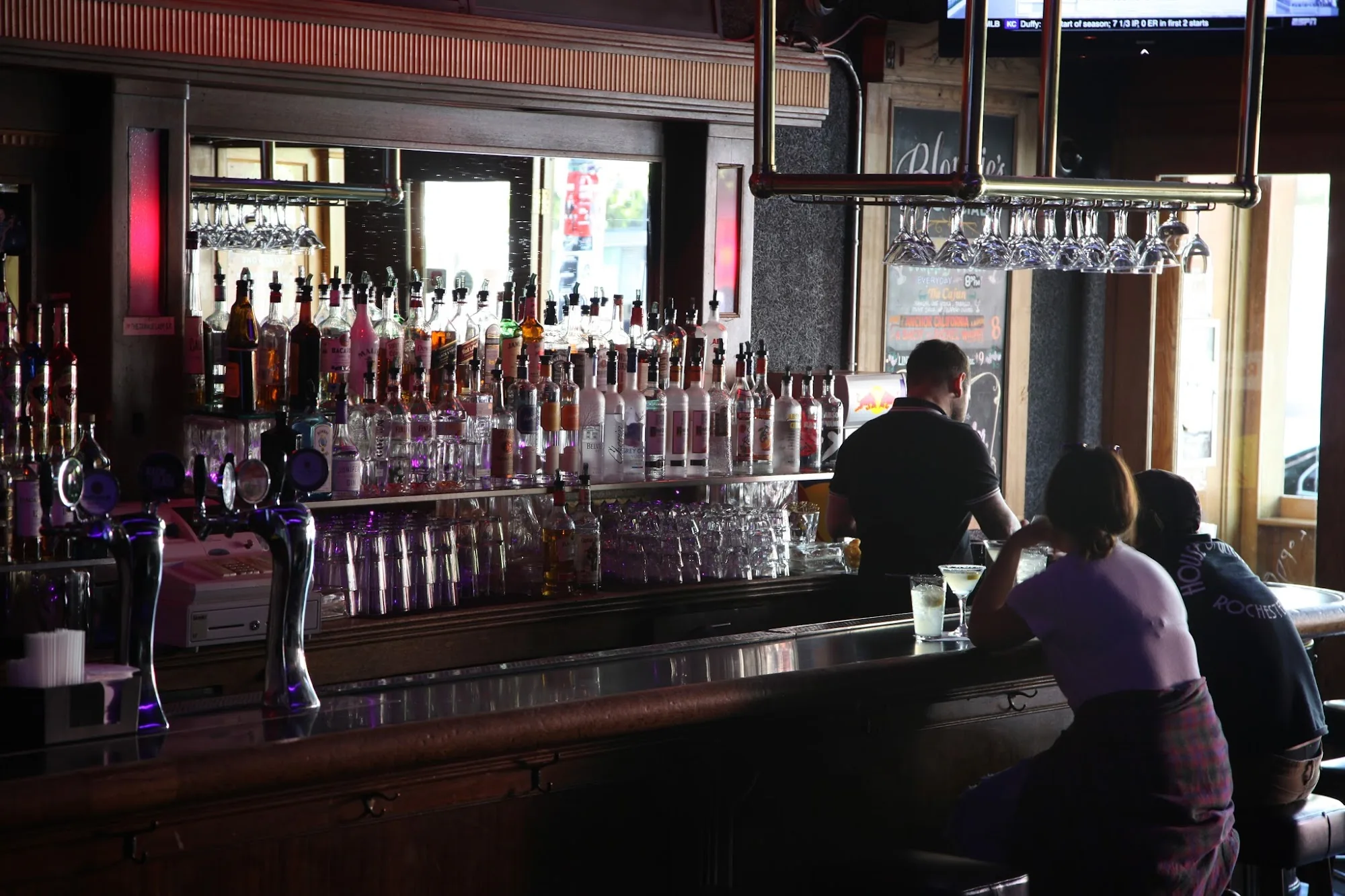 Wide view of the long backbar and bottle wall inside Blondie's Bar San Francisco with patrons at the counter