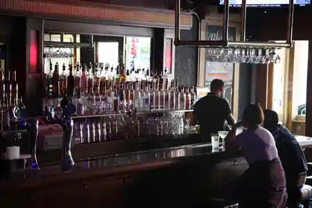 Wide view of the long backbar and bottle wall inside Blondie's Bar San Francisco with patrons at the counter — salsa venue in San Francisco