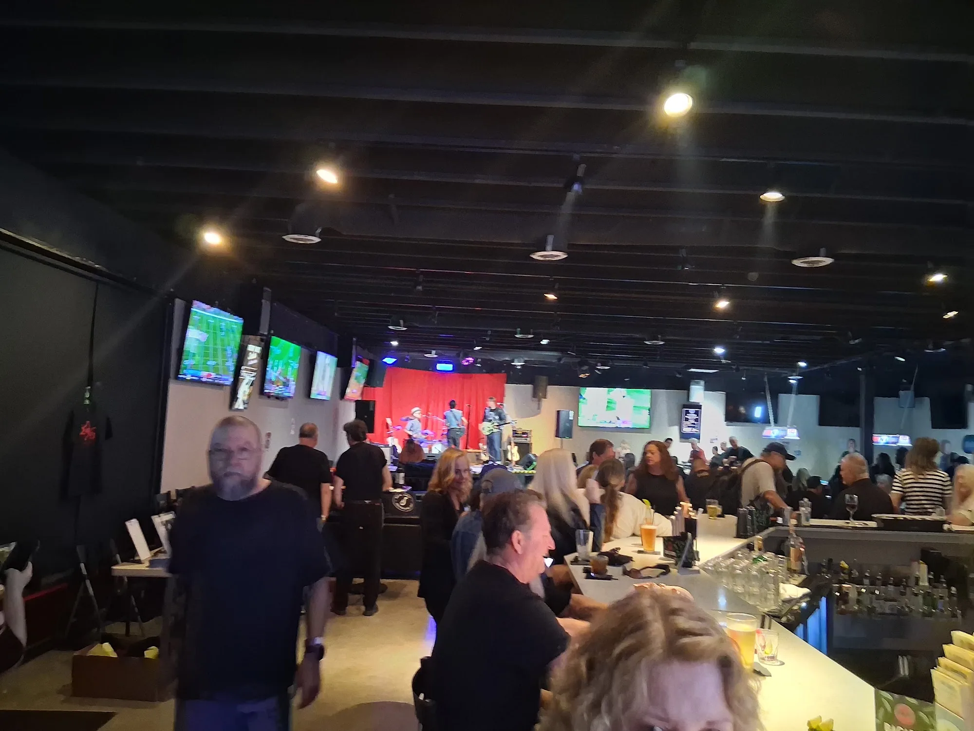 Live band on stage with a crowd inside The Mamba sports bar in Huntington Beach
