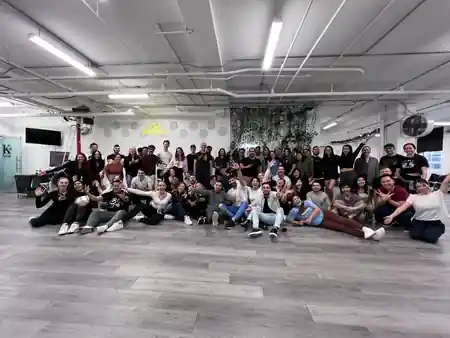 Group photo of dancers under the KTown neon sign at KTown Dance Studio in New York — bachata, salsa, kizomba venue in New York