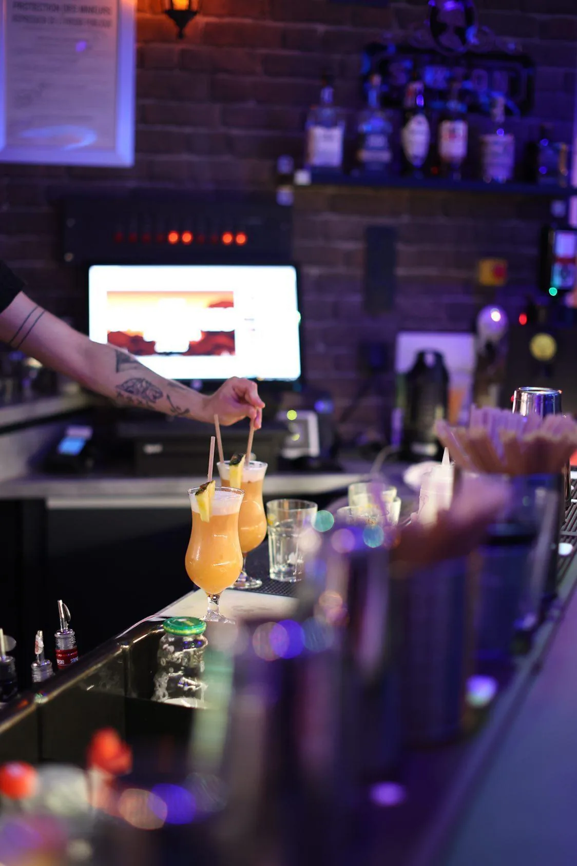 Full bar counter at Le 140 with bartender serving cocktails under club lighting