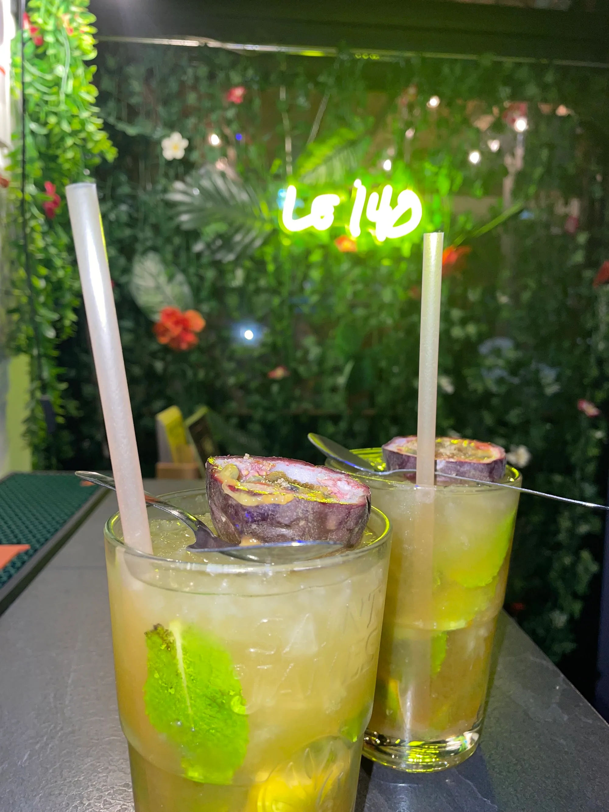 Two cocktails on a table with the Le 140 neon sign visible in the background
