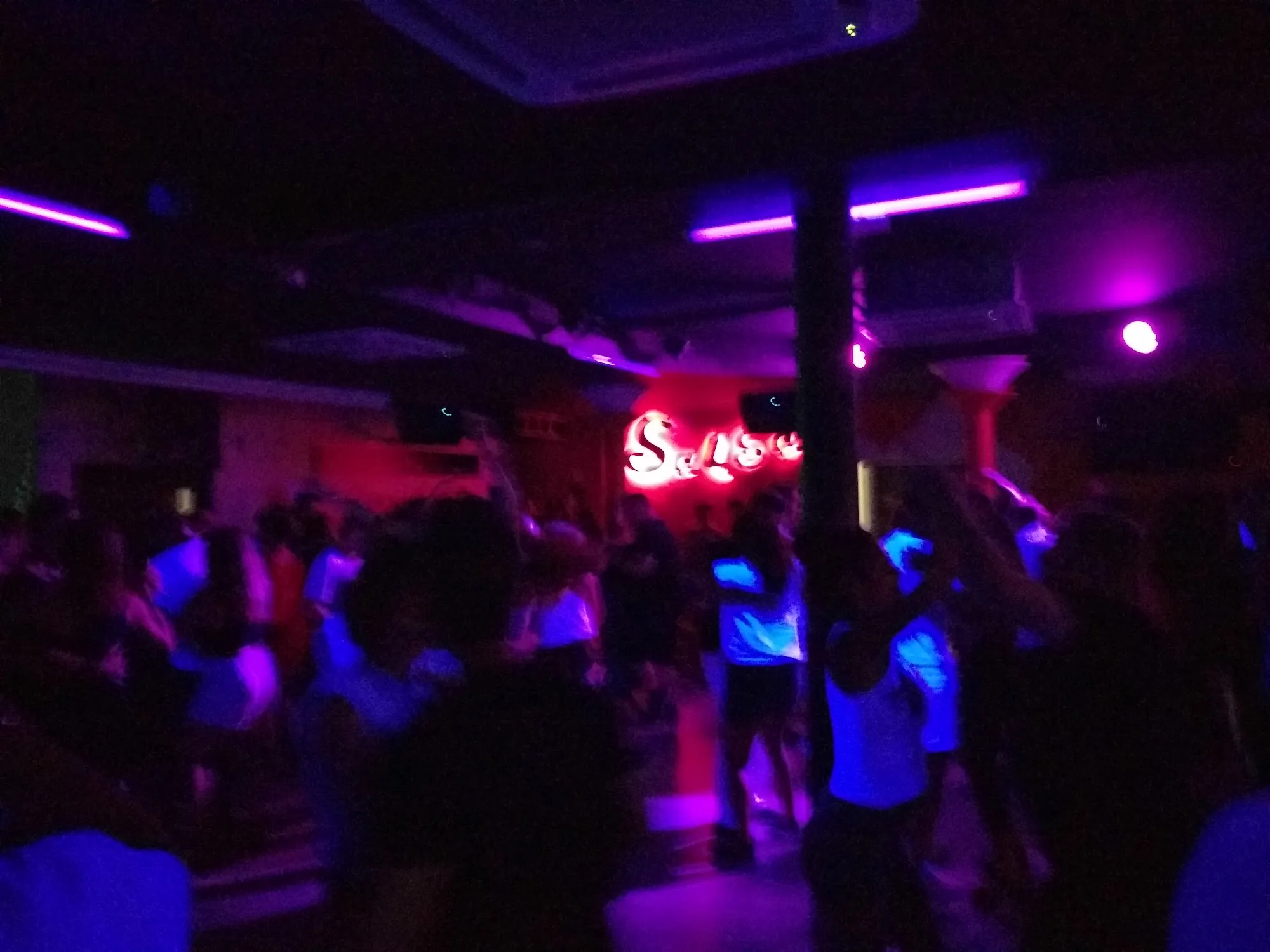 Packed dance floor crowd with Salsa neon sign at Sala Muévete Málaga