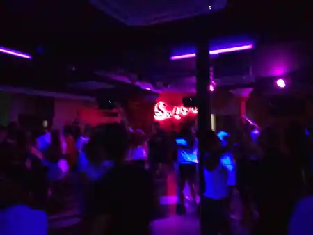 Packed dance floor crowd with Salsa neon sign at Sala Muévete Málaga