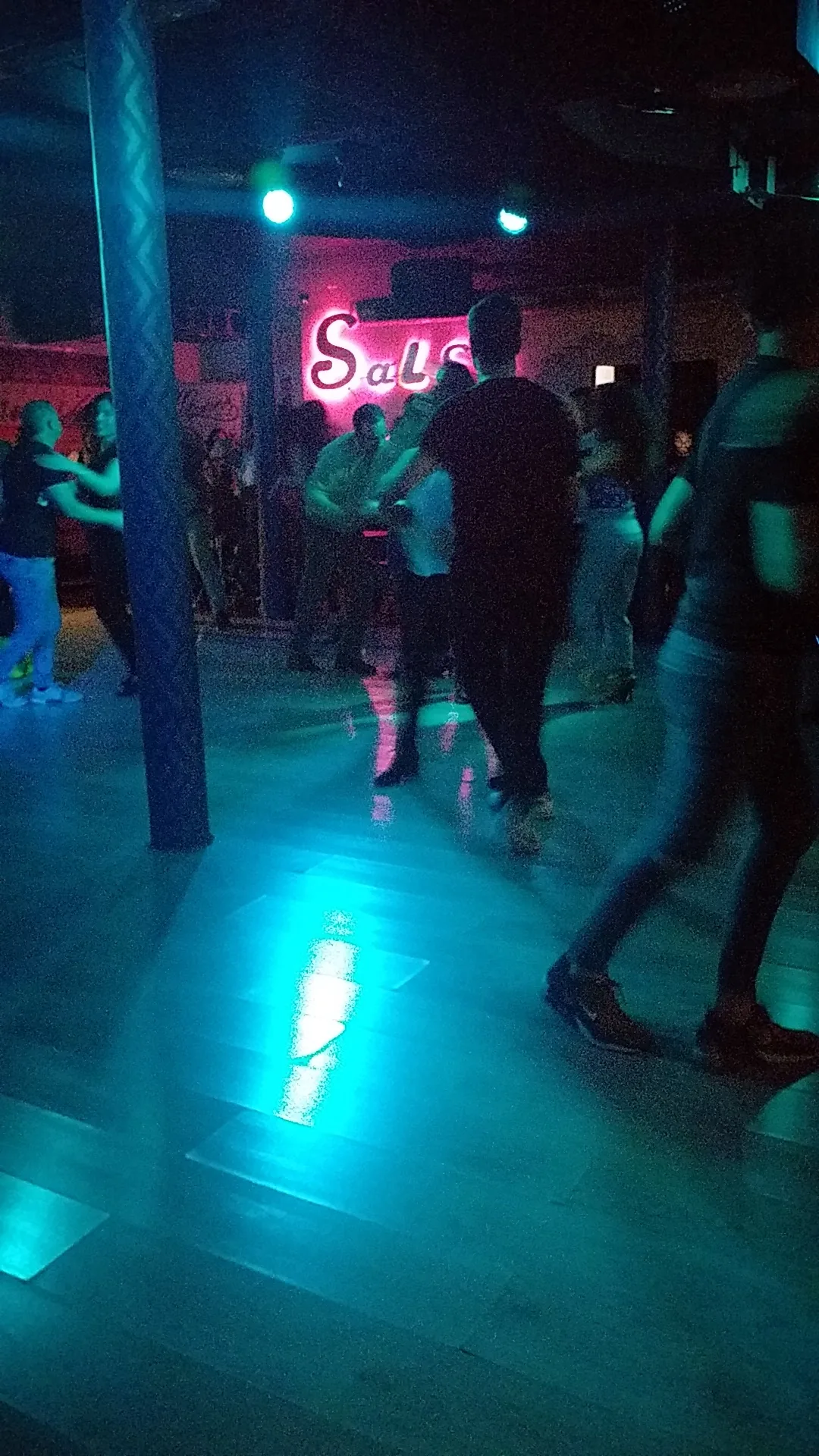 Couple dancing salsa with neon sign in background at Sala Muévete Málaga