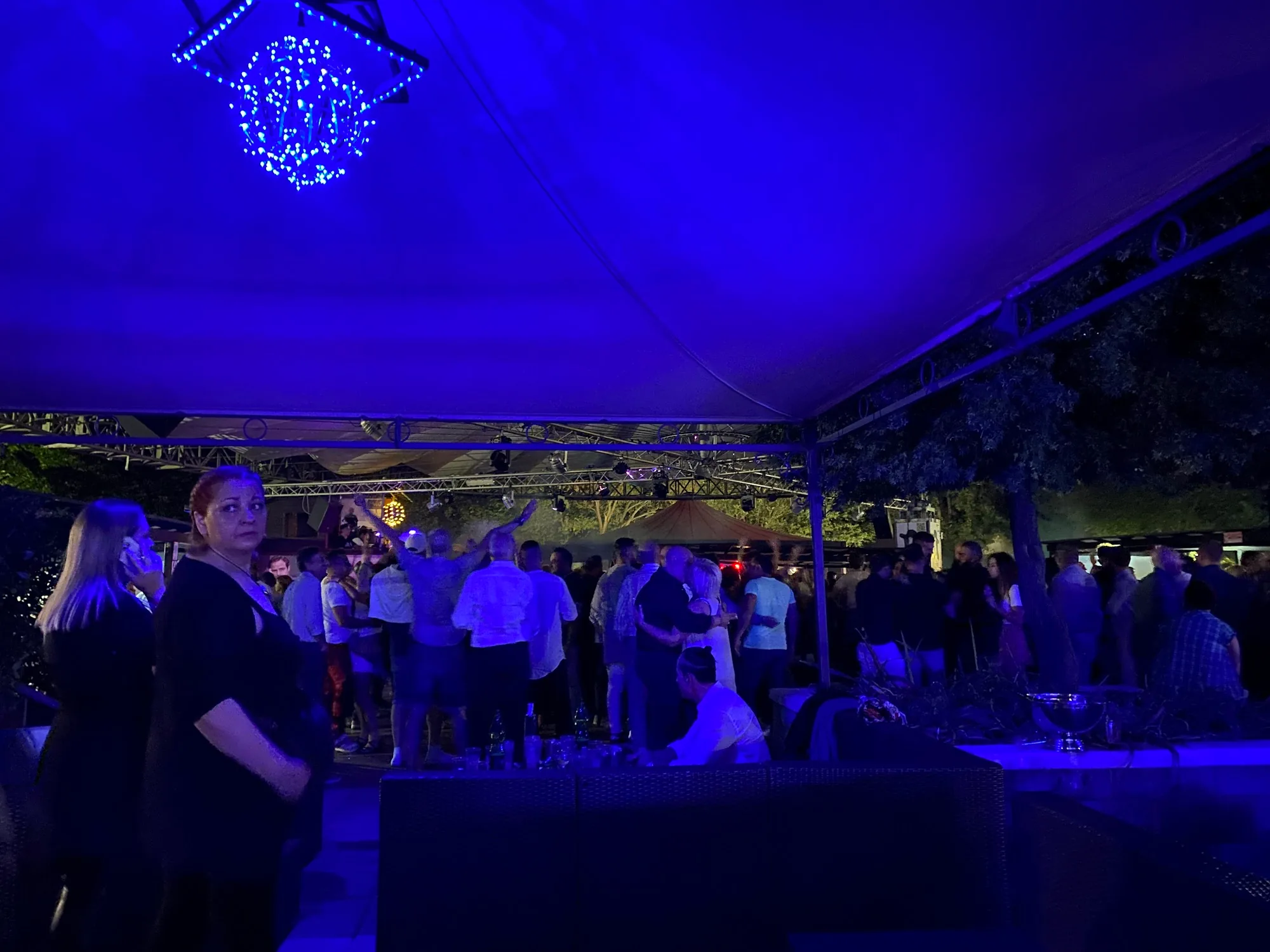 Penelope Beach outdoor club Torino — evening crowd on terrace with large stage tent and trees