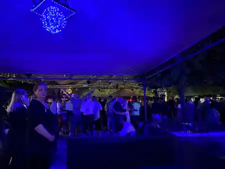 Penelope Beach outdoor club Torino — evening crowd on terrace with large stage tent and trees — salsa, bachata venue in Torino