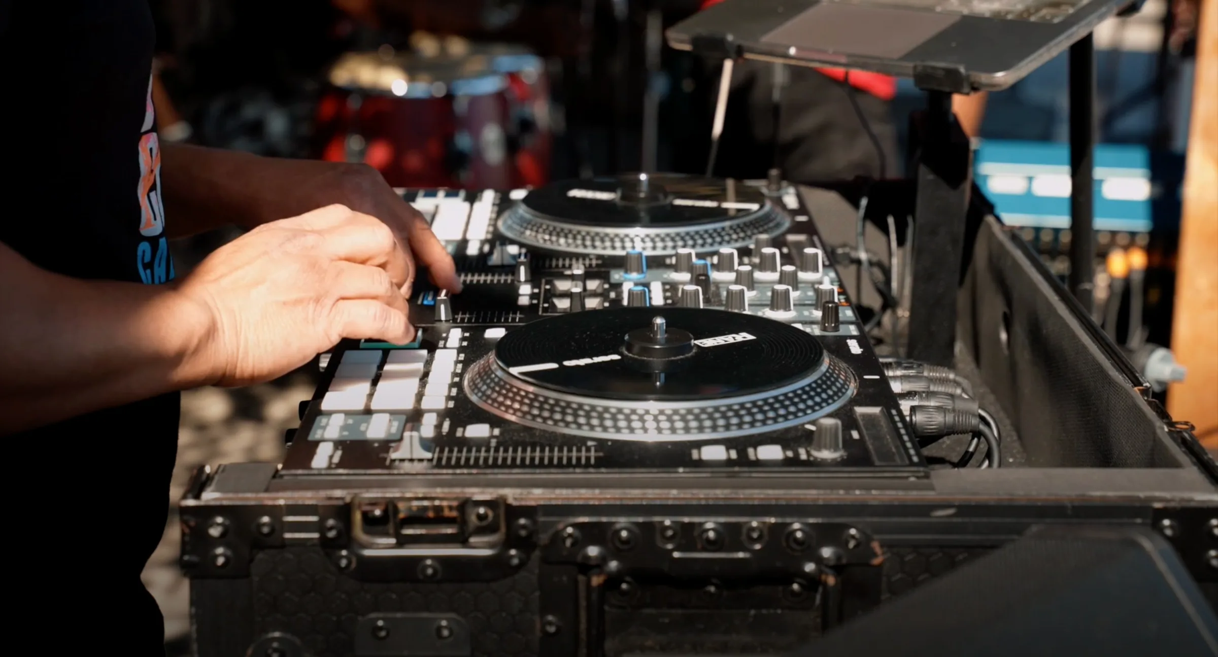 Close-up of a DJ mixing on turntables next to a drum kit at an outdoor live-music dance event at The Ramp Restaurant, San Francisco.