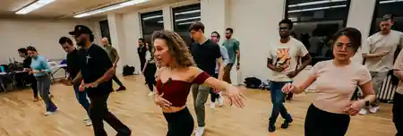 Dance class at 230 Fifth in New York City with dancers practicing salsa and bachata moves on a wooden studio floor