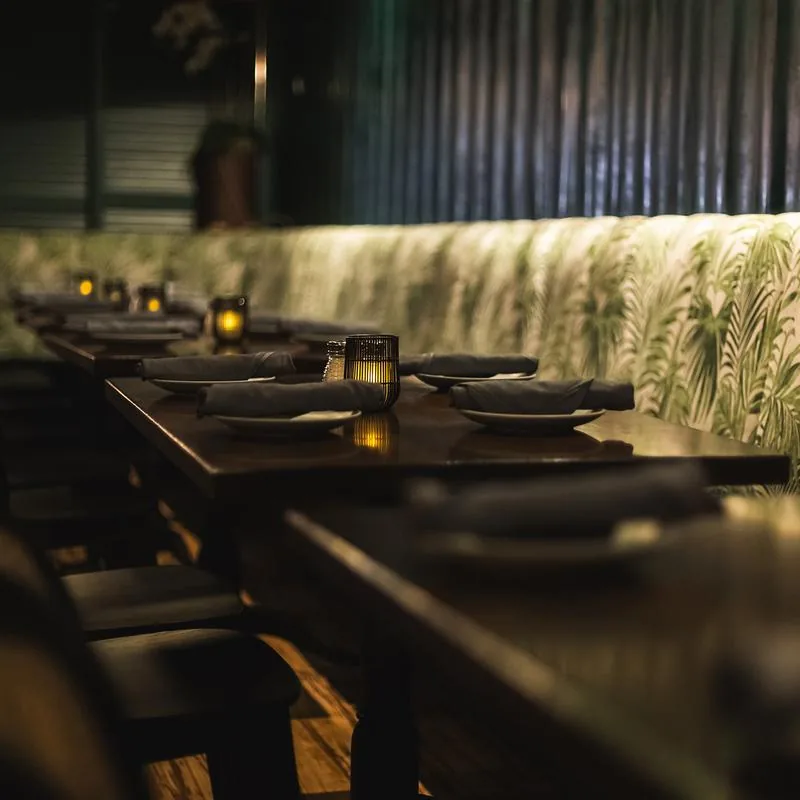 Tropical-print banquette seating with candlelit tables at Negril Village New York
